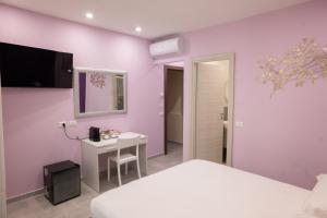 a bedroom with purple walls and a white bed and a desk at Affittacamere CINQUE TERRE LABI in La Spezia