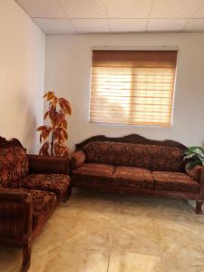 a living room with two leather couches and a window at دار زمان Zaman Suites Old Town in Al Mafraq