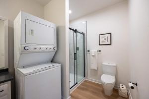 een witte badkamer met toilet en douche bij Modern Downtown Studio - Bike or Walk to Trails & Dining in Bentonville