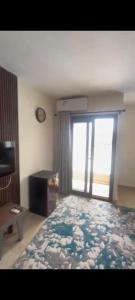 ein Schlafzimmer mit einem großen Fenster und einem Bett mit einer Decke in der Unterkunft Grand hills Resort north coast in Dawwār Abū Maḩrūs