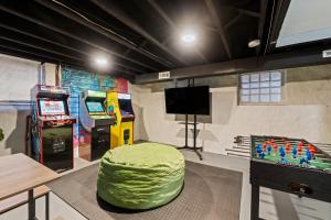 a room with two arcade games and a green ottoman at The Journey Home | JZ Vacation Rentals in Soulard
