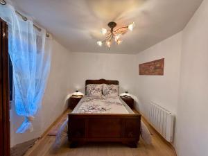 a bedroom with a bed with blue curtains and a chandelier at L’Angelina in Martrin +4 photos