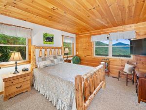 a bedroom with a bed and a flat screen tv at Mountain Air Hot Tub-Fire Pit in Bryson City +52 photos