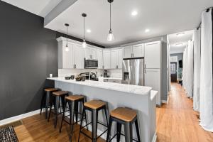 a kitchen with white cabinets and bar stools at The Journey Home | JZ Vacation Rentals in Soulard