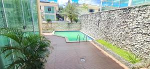 a swimming pool next to a stone wall and a building at Cop 30 - Casa em Condominio Oasis in Ananindeua