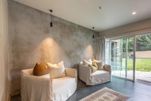Dos sillas blancas en una sala de estar con una pared. en Stone Cottage, en Arrowtown