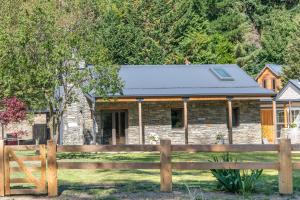ein Steinhaus mit einem Zaun davor in der Unterkunft Stone Cottage in Arrowtown