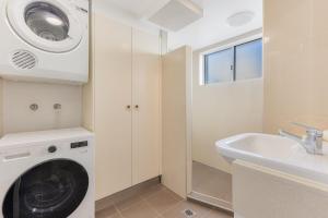 a bathroom with a washing machine and a sink at Beach Lodge Unit 5 in Gold Coast