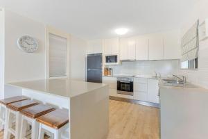 a kitchen with white cabinets and a counter with stools at Beach Lodge Unit 5 in Gold Coast