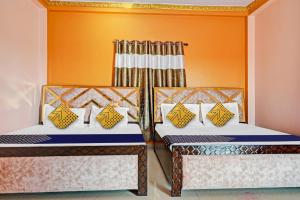 GuwārighātHotel O Maa Narmada的橙色墙壁客房的两张床