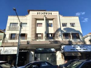 a white building with a bridge over a street at Pousada Sâo Luiz in Poços de Caldas