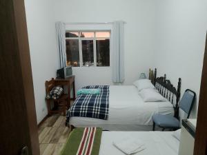 a small bedroom with two beds and a window at Pousada Sâo Luiz in Poços de Caldas