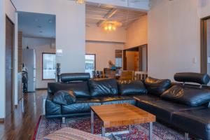 a living room with a leather couch and a table at 源泉かけ流し温泉付き一棟貸しVilla Gensen Two in Yuzawa
