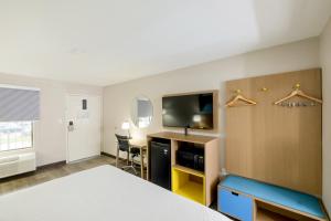 a hotel room with a bed and a flat screen tv at Days Inn & Suites by Wyndham Bossier City - Casino Area in Bossier City
