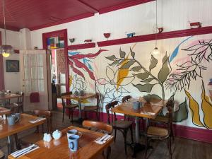 a restaurant with wooden tables and a painting on the wall at Hôtel-La Grande Maison et Spa in Baie-Saint-Paul