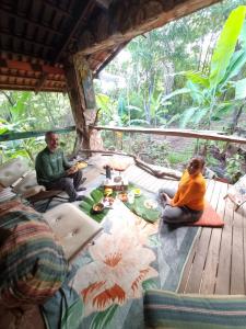 two people sitting on a wooden deck in a tree house at Castelo de pedras no Vale da Lua in Alto Paraíso de Goiás