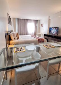 une chambre d'hôtel avec un lit et une table en verre dans l'établissement Coral Ritz - Flat beira mar (Condomínio Ritz Suites Home Service), à Maceió