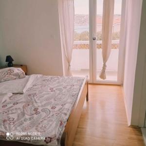 ein Schlafzimmer mit einem Bett und einem großen Fenster in der Unterkunft Apartment Barbat 22 in Barbat na Rabu