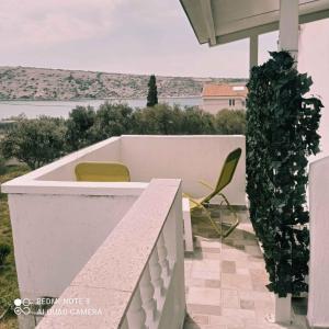 ein Balkon mit einer Bank und einem Stuhl und einer Aussicht in der Unterkunft Apartment Barbat 22 in Barbat na Rabu