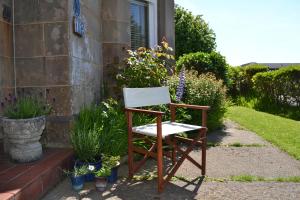 a chair sitting outside of a house with flowers at Maybank Guest House in Helensburgh +5 photos