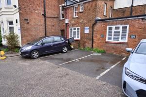 a car parked in a parking lot in front of a brick building at Apartment in Buckinghamshire with Secured Parking in Buckinghamshire