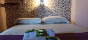 a bed with two pillows and a brick wall at Pousada - Casa dos Paiva in Barreirinhas