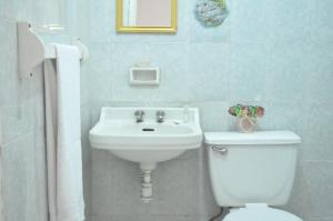 y baño con aseo blanco y lavamanos. en Hotel San Carlos, en Irapuato