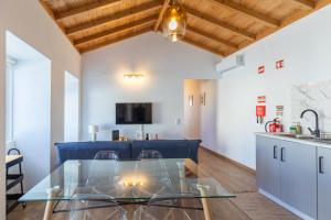 a kitchen and a dining room with a glass table at Ti Chôa - Ninho dos Avós in Santa Bárbara