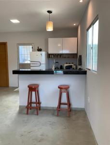 a kitchen with two stools and a counter top at Casa Aconchegante com Piscina in Porto Seguro
