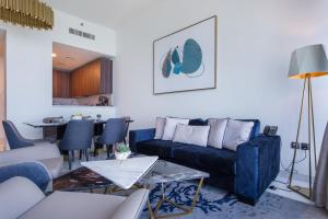 a living room with a blue couch and a table at Maison Privee - Chic Coastal Escape with Open Sea Vws on Palm Entry in Dubai