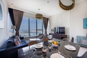 a living room with a blue couch and a table at Maison Privee - Chic Coastal Escape with Open Sea Vws on Palm Entry in Dubai