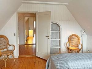 スヴァネケにある6 person holiday home in Svanekeのベッドと椅子2脚と廊下のある寝室