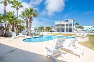 a swimming pool with white chairs and a house at Blue Fin House- Pet Friendly & Boardwalk to the Beach! in Mustang Beach