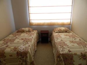 two beds in a small room with a window at Depto Puertas del Mar La Serena in La Serena