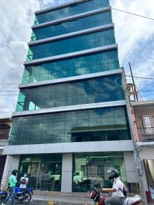 ein hohes Glasgebäude mit Menschen auf Rollern davor in der Unterkunft Apartamento en el centro de Matagalpa in Matagalpa