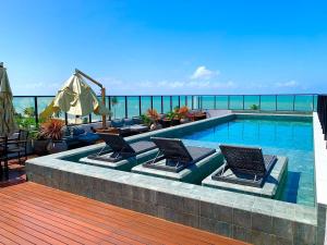 a swimming pool with chairs and a deck with the ocean at Espaço e conforto em frente ao mar in João Pessoa