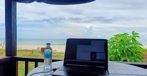 a laptop computer sitting on a table with a view of the beach at Mangazou Beach Chalet in Kudat