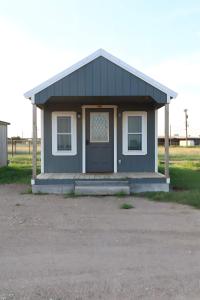 a small blue house with a porch and a door at Charming small cabin in Floydada