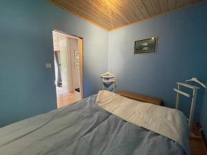 a bedroom with a bed in a blue wall at Peaceful Cabin near Furufjall Trail in Spekeröd