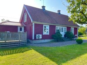 a red house with a fence in a yard at 4 star holiday home in KÖPINGSVIK in Köpingsvik