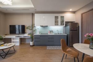 eine Küche mit weißen Schränken und einem Kühlschrank und Tischen in der Unterkunft Delux 2Bedroom Near Marriott And Dcapital With Swimming Pools And Gyms in Hanoi