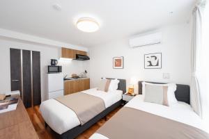 two beds in a hotel room with a kitchen at 銀座線徒歩9分 松が谷アパート in Tokyo