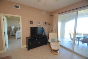 a living room with a flat screen tv and a chair at Surf Club I, 1405 in Marineland