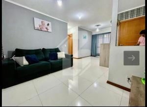 a living room with a green couch in a room at Apartamento próximo ao centro e Havan in Gravataí