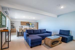 a living room with blue couches and a kitchen at Viva Jaco in Jacó