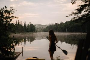 Eine Frau steht mit einem Paddel vor einem See. in der Unterkunft Chalet Mazama - Private Lake - Hot Tub - 16P in Wentworth-Nord