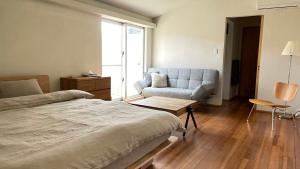 Un dormitorio con una cama, un sofá y una silla. en ふくぎリビング - Fukugi Living, en Motobu