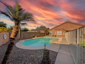 a swimming pool with a palm tree in front of a house at Kimberly Surprise in Surprise