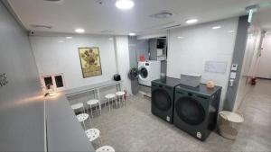 a laundry room with a washing machine and chairs at All Stay Hostel in Seoul