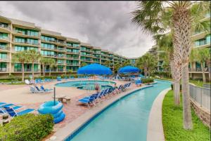 奥兰治比奇Charming 2bd/2ba w/ Bay View, Pool w/ Lazy River的度假村的游泳池,设有蓝色的椅子和棕榈树